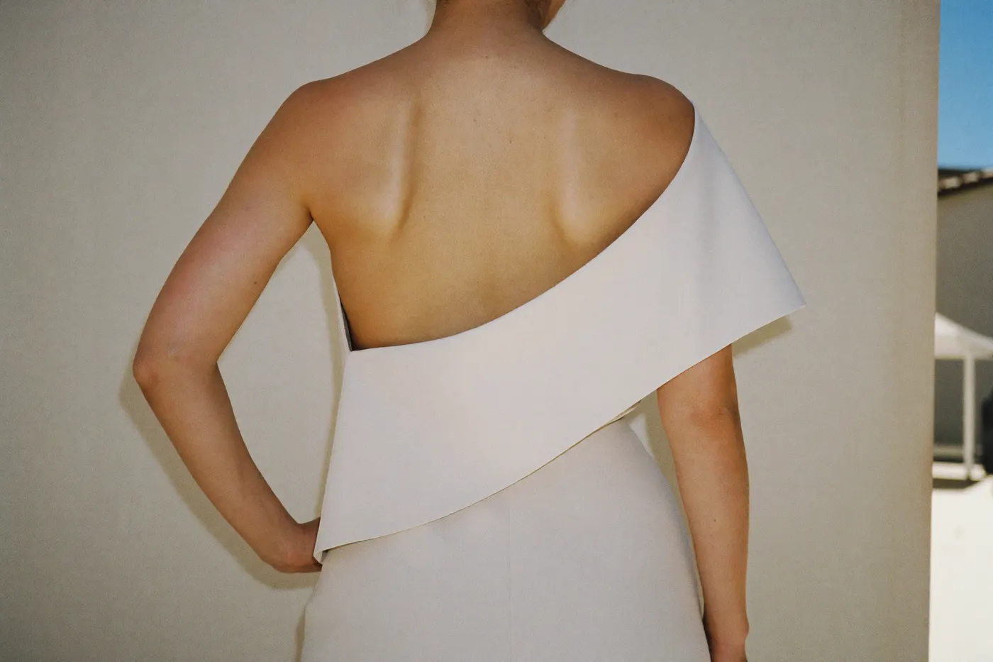 Asymmetrisches Brautkleid mit One-Shoulder-Linie, Braut von hinten in ruhigem Licht