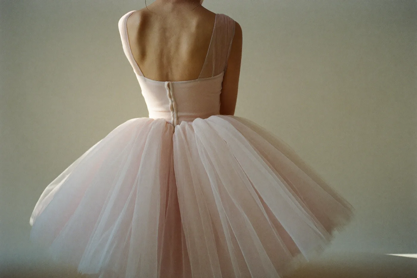 Braut von hinten im Brautkleid in Blush mit zartem Rosé-Unterton und fließendem Tüllrock