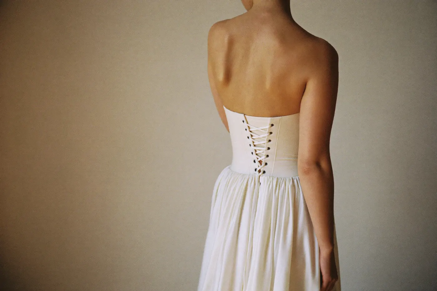 Braut von hinten im trägerlosen Brautkleid mit Corsage und Schnürung