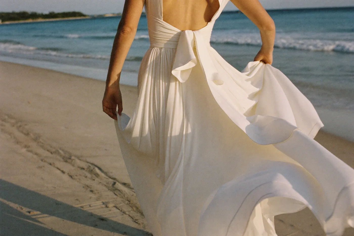 Braut von hinten im fließenden Chiffon Brautkleid am Strand