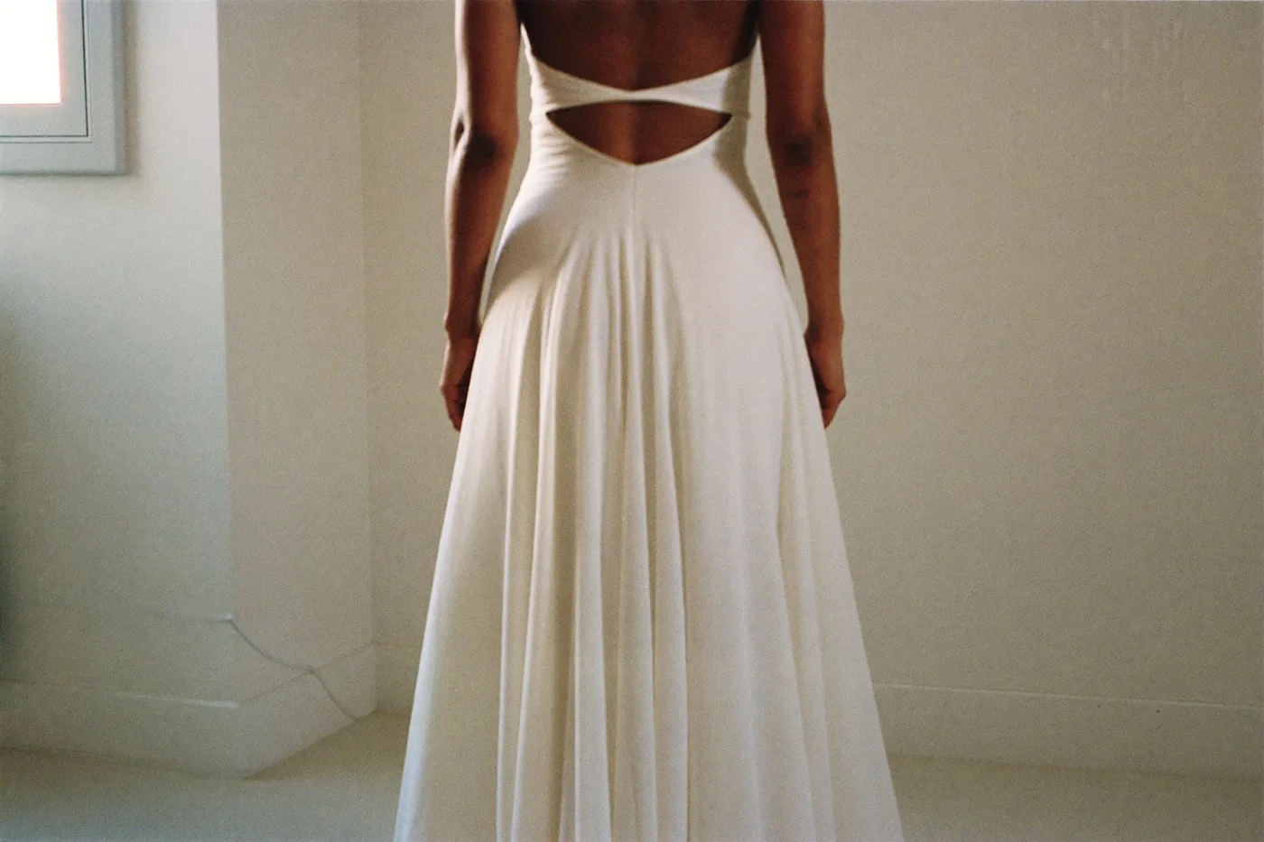 Empire Brautkleid mit hoher Taille und fließendem Rock, Braut von hinten in warmem Tageslicht