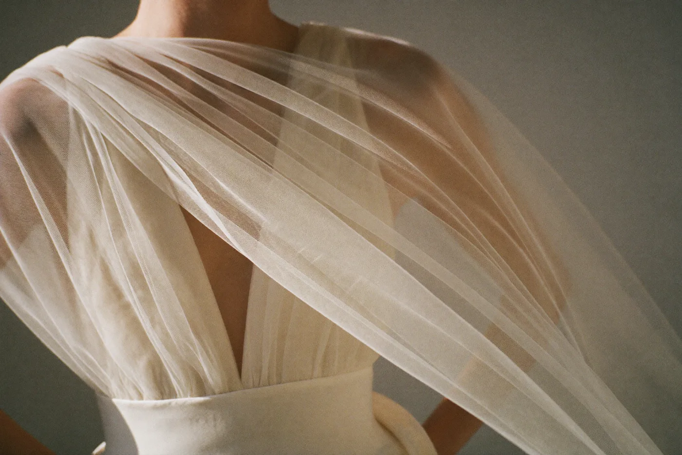Zarte Chiffon- und Tülllagen eines Empire Brautkleids in Nahaufnahme, warmes Tageslicht