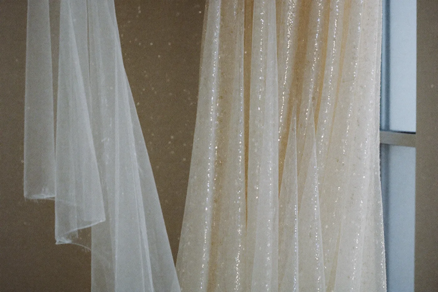Glitzer Brautkleid im Detail: feine Pailletten und Glitzertüll fangen weiches Tageslicht ein