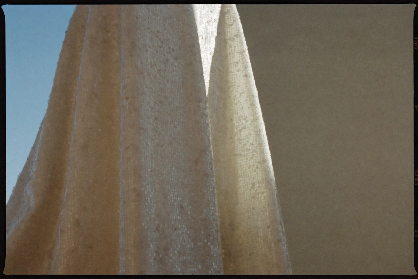 Glitzer Brautkleid mit feinen Pailletten, die im weichen Tageslicht schimmern, ruhige Detailaufnahme des Stoffes