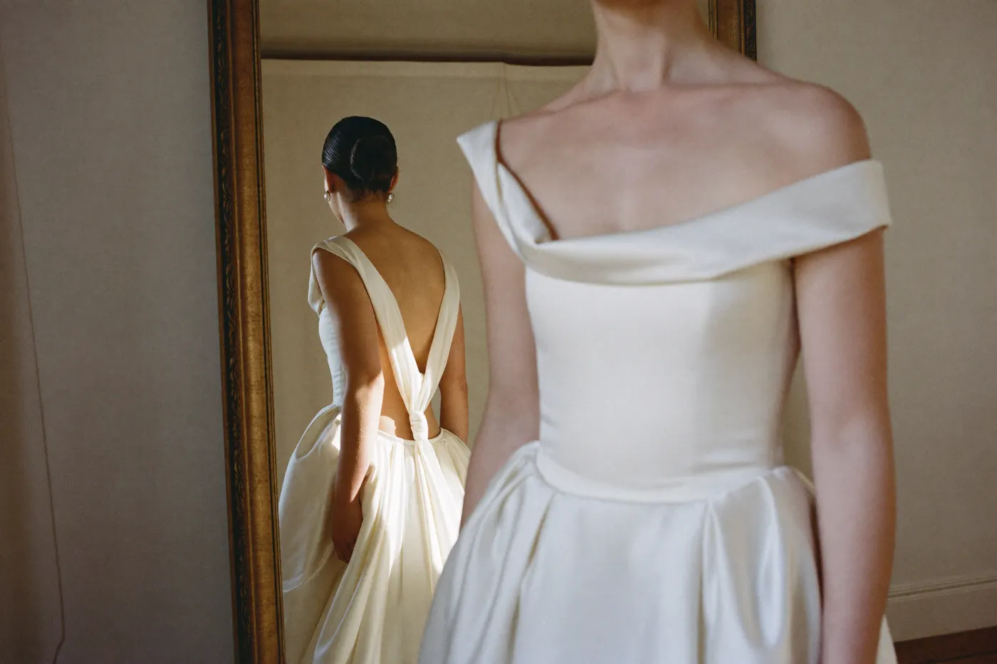 Ivory Brautkleid bei der Anprobe vor dem Spiegel, warmes Licht im Atelier