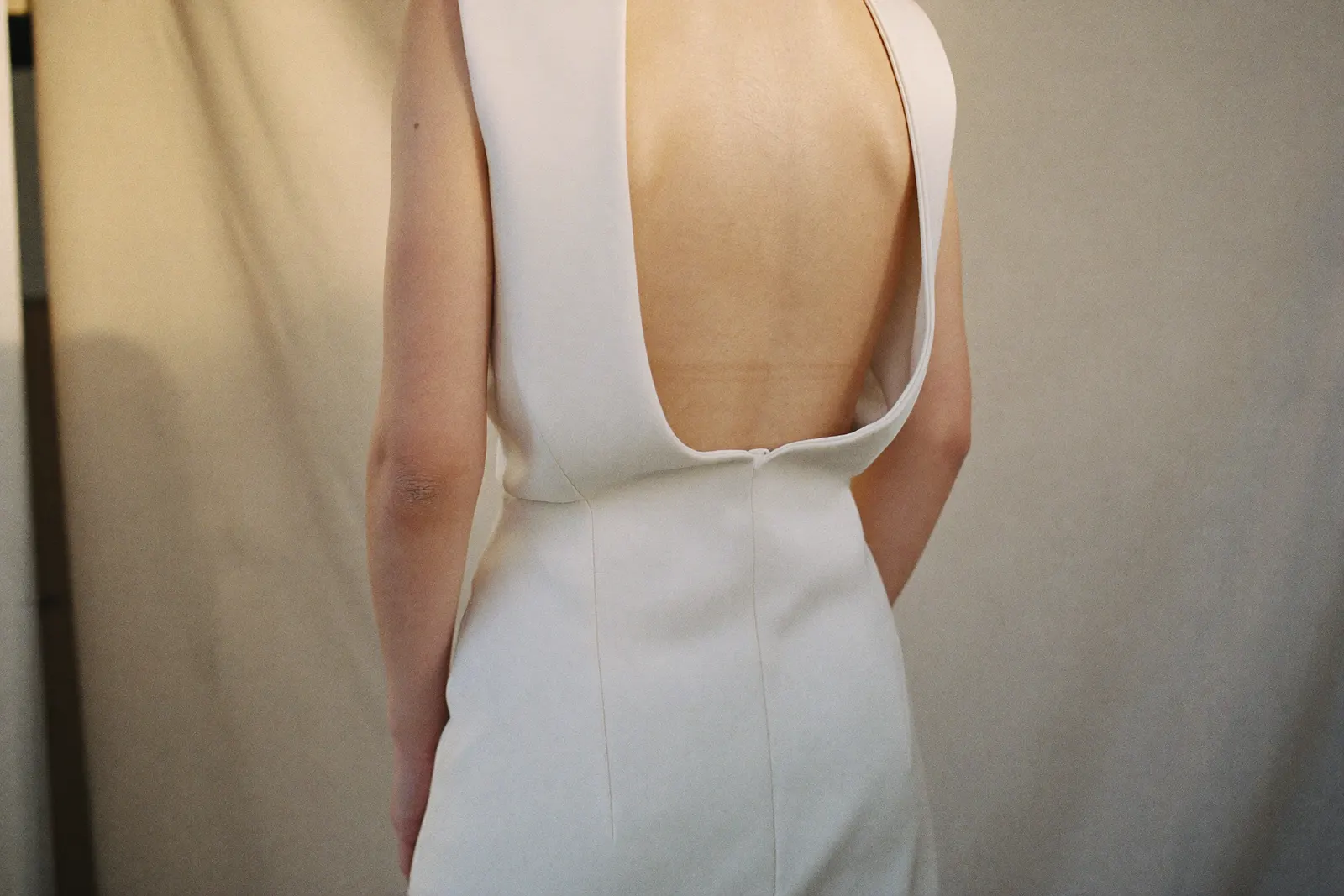 Modernes Brautkleid mit klarer Silhouette und tiefem Rückenausschnitt in weichem Tageslicht, von hinten fotografiert