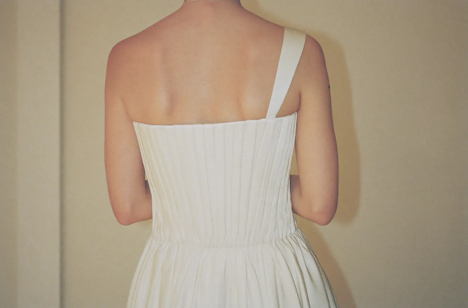 One-Shoulder Brautkleid mit asymmetrischem Träger, Braut von hinten in warmem Tageslicht