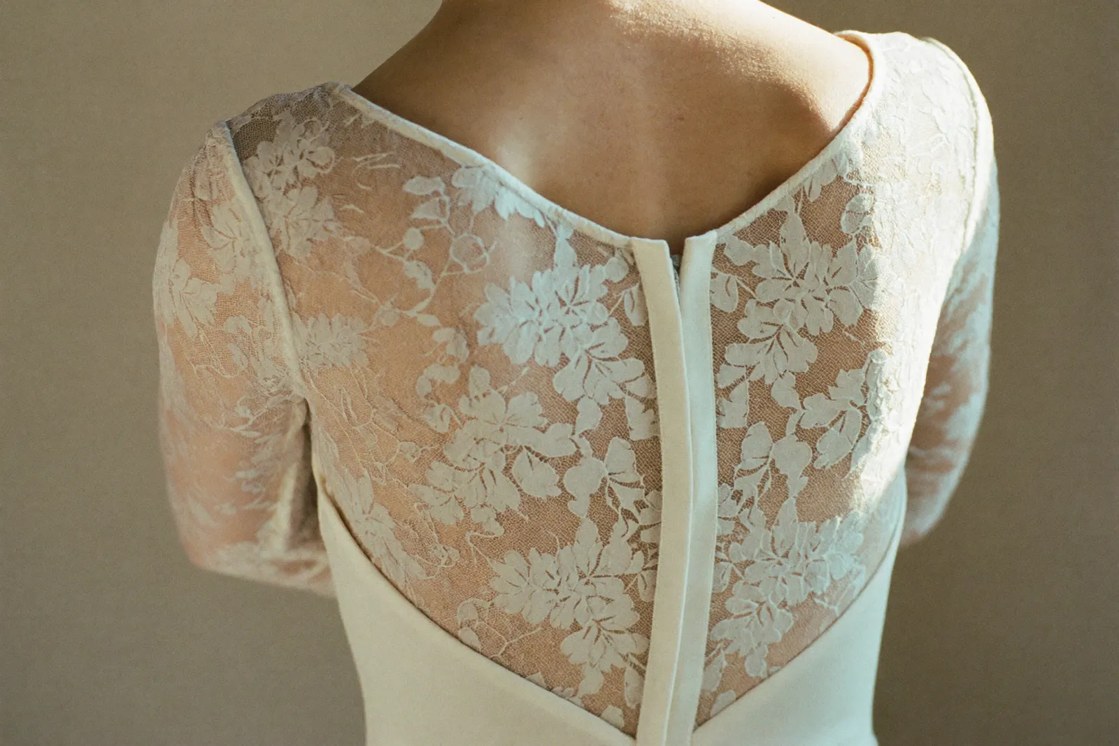 Modernes Spitzen-Brautkleid aus feiner Spitze, ruhig in weiches Licht gesetzt, Stoffstruktur im Fokus