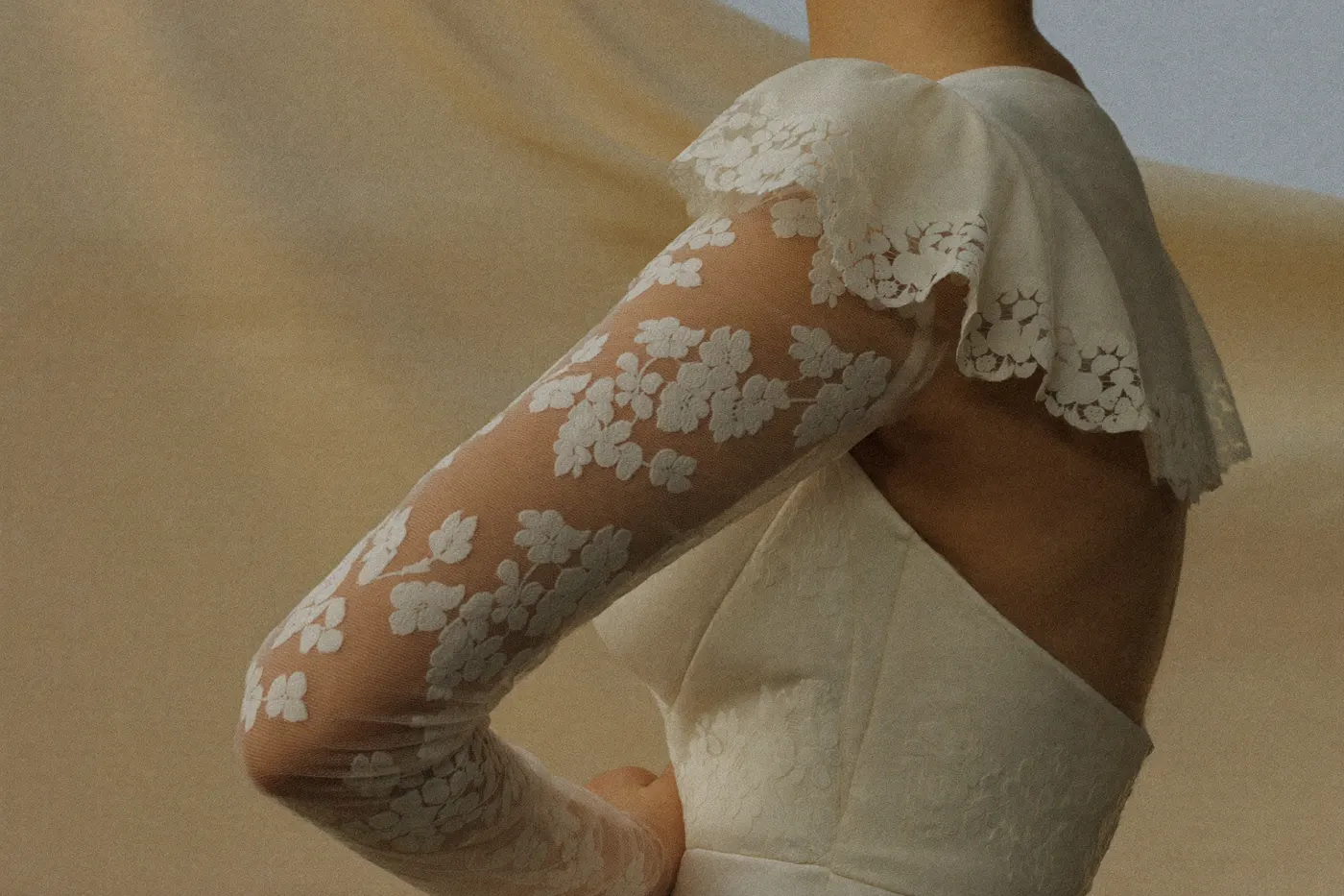 Brautkleid mit Spitzenärmeln: Nahaufnahme zarter floraler Spitze am Arm der Braut