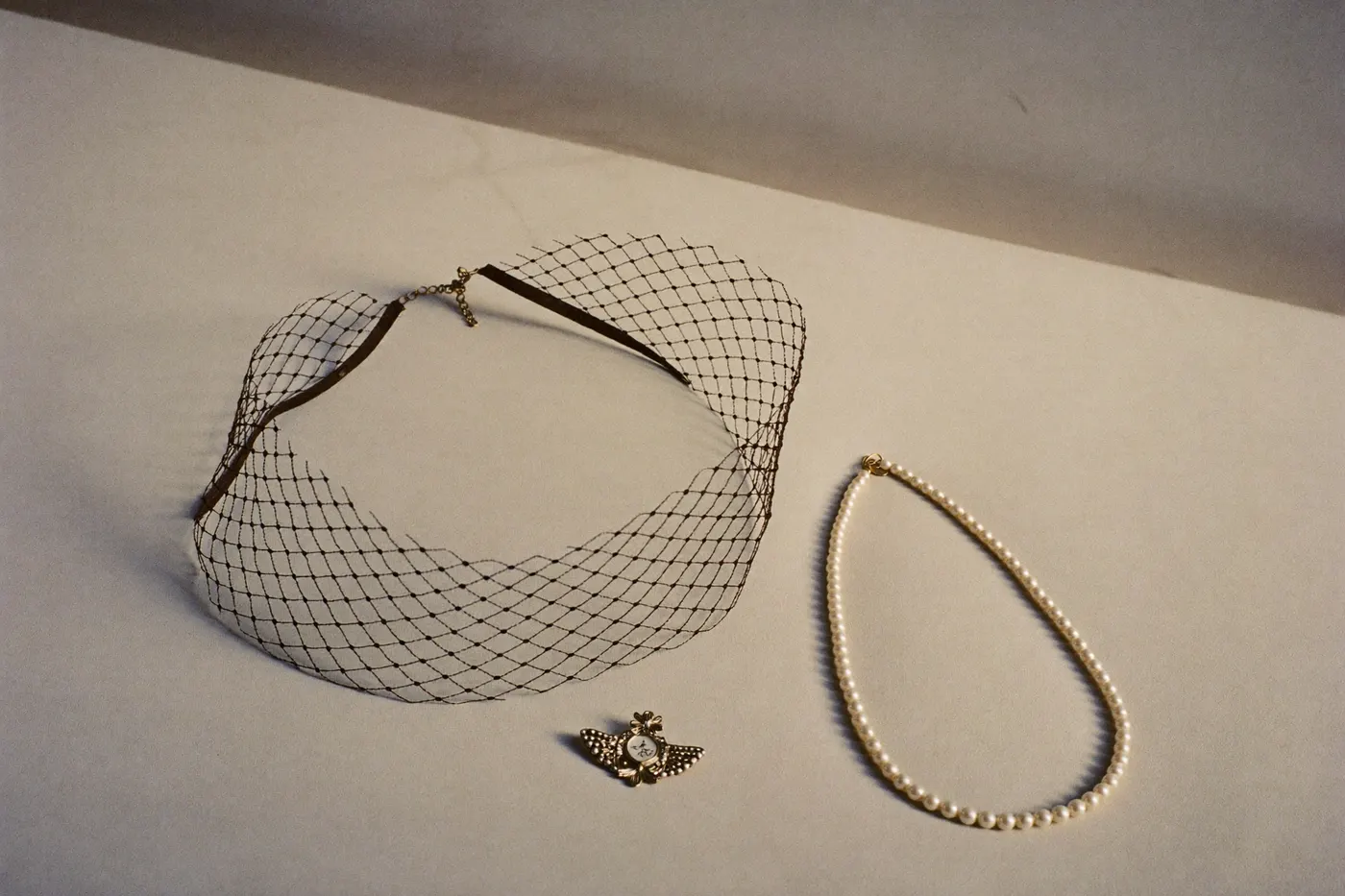 Vintage-Brautaccessoires wie Birdcage-Schleier und Perlenkette auf hellem Stoff