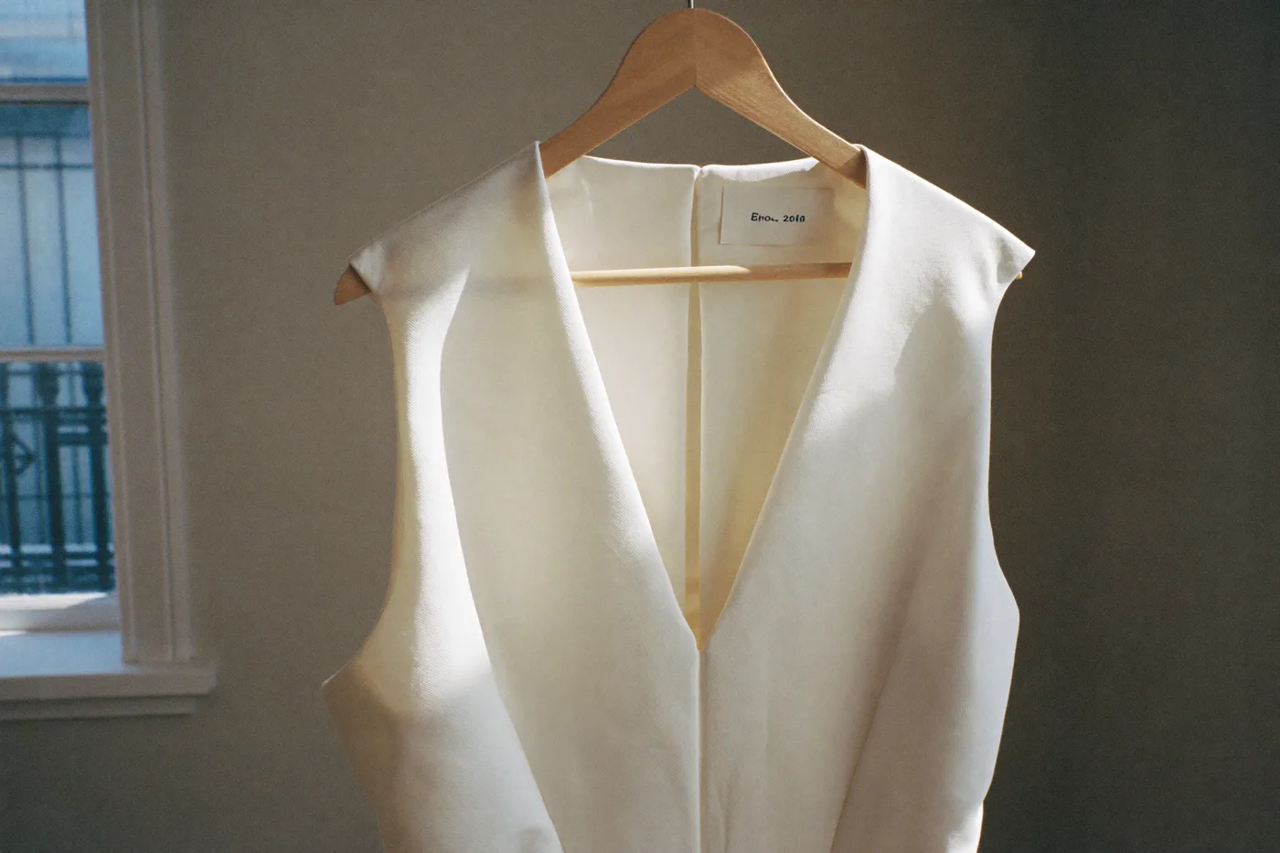 Weißes Brautkleid am Bügel im Atelier, weiches Tageslicht auf glattem Stoff
